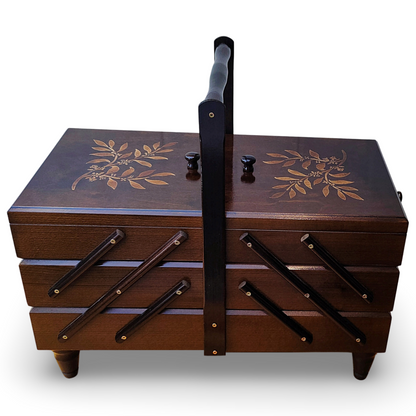 An extra large wooden sewing box with dark walnut color and leaf branch patterns on the lid, equipped with a handle and accordion-style drawers.